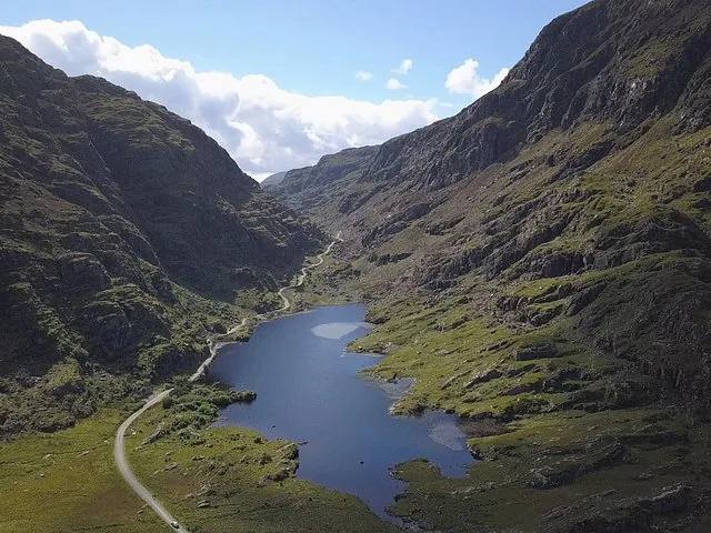 Aerial view of a dark blue lake in a valley surrounded by steep, rocky mountains