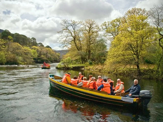 Tourists on a small motorboat ride down a scenic river surrounded by green trees